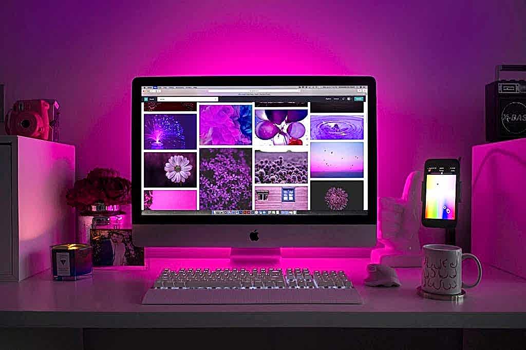 Modern desk setup with neon lighting and a desktop computer displaying colorful images. ankara en iyi web tasarim ajansi