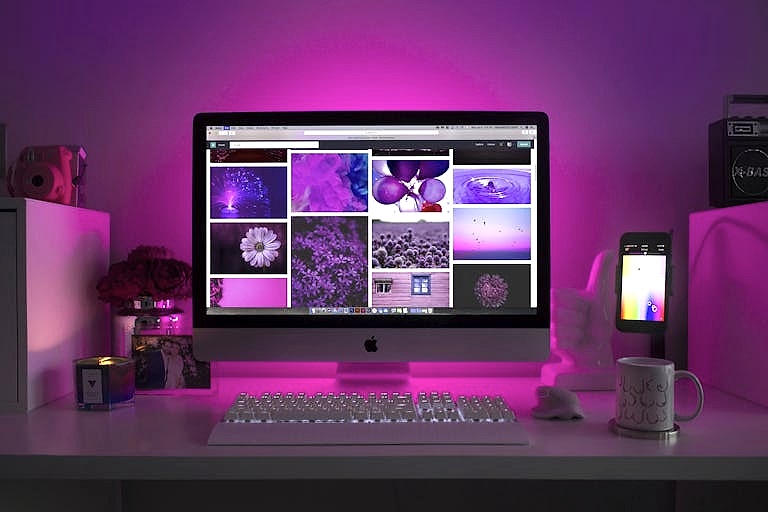 Modern desk setup with neon lighting and a desktop computer displaying colorful images. ankara en iyi web tasarim ajansi