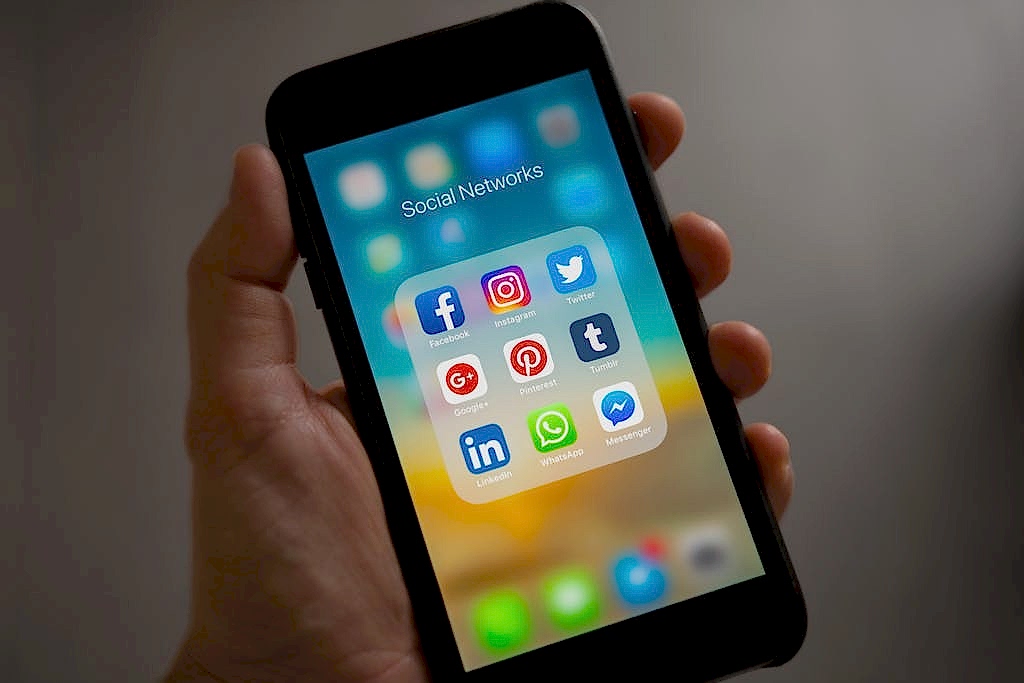 A smartphone displaying various social media icons held in a hand, showcasing modern communication apps. Ankara kurumsal instagram hesap ve reklam yönetimi